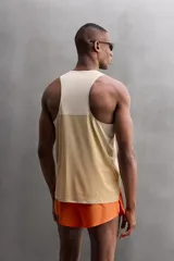 Camiseta deportiva sin mangas color beige, confeccionada en tejido técnico ligero y elástico con estructura perforada. Tiene cuello redondo amplio, sisas con acabados termofijados, bajo con aberturas laterales y logo estampado.