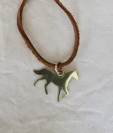 Gargantilla con cordón de cuero marrón y dije de caballo de bronce.