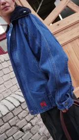 Campera de jean azul con corte oversize, solapa de corderito y pin decorativo.