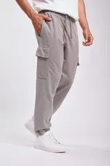 Pantalón deportivo tipo jogger color gris con bolsillos cargo laterales y tobillos ajustados.