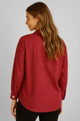 Blusa blanca de poliéster, corte holgado, con cuello camisero y cierre parcial con botones.