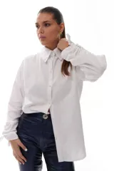 Camisa blanca de algodón con cuello clásico, mangas largas con puños fruncidos y cierre de botones al frente. Presenta frunces y lazo ajustable en la espalda.