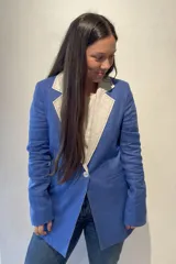 Blazer azul de lino con corte entallado, solapas y cuello combinados en color gris, botón de nacar, tajo trasero y bolsillos laterales.