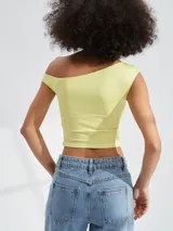 Top corto color amarillo, con escote asimétrico y un solo tirante ancho.