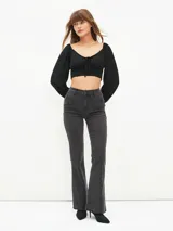 Blusa crop top negra con escote cuadrado, mangas largas abullonadas y lazo ajustable en el centro del busto.