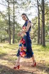 Vestido midi azul marino con estampado de flores rojas, naranjas y rosas. Tiene cuello drapeado y corte ajustado al cuerpo.