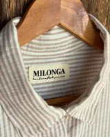 Camisa a rayas verticales, con cuello clásico y cierre frontal con botones.