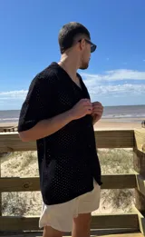 Camisa negra tejida con diseño calado, manga corta y corte regular.