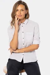 Camisa blanca de lino lisa, de manga larga, con botones metálicos personalizados, dos bolsillos en el pecho y presilla en la manga.