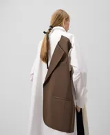 Camisa oversize blanca de manga larga con cuello solapa y botonadura frontal. Presenta una pieza superpuesta en la espalda que corresponde al delantero de un blazer.