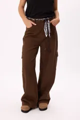 Pantalón cargo marrón de corte ancho con bolsillos laterales y cinturón de tela estampado.