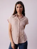 Camisa color crema con bordado de hojas color marrón, cuello con solapa, manga corta y cierre frontal con botones.