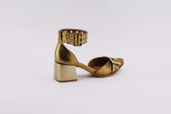 Zapato de cuero color dorado con punta fina, taco cuadrado y pulsera con hebilla y ojales.