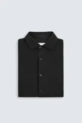 Camisa color beige de corte slim fit, confeccionada en tejido elástico que minimiza las arrugas. Tiene cuello italiano abierto, manga larga con puños abotonados y cierre frontal con botones.