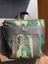 Mochila pequeña color borgoña con detalles en cuero marrón, asa de mano y correas ajustables.
