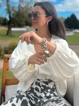 Blusón blanco de mangas largas abullonadas con puños elásticos y escote en V.