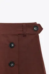Falda pantalón color marrón óxido de tiro medio, con falsos bolsillos de vivo en la espalda y cierre frontal cruzado con botones y lateral con cremallera oculta en la costura.