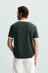 Camiseta azul marino de corte regular, con cuello redondo y mangas cortas. Presenta ribete blanco en cuello y mangas.