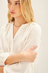 Camisa blanca de poliéster con cuello mao y mangas largas con frunces en hombros, mangas y espalda.