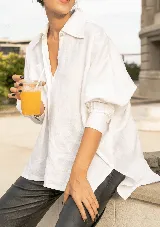 Camisa oversize blanca confeccionada en lino, con cuello camisero clásico, cartera con botones de nácar a la vista y puños con tablitas.