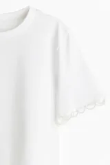 Remera blanca de algodón con cuello redondo y mangas cortas con detalle de puntilla.