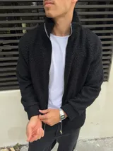 Campera negra símil corderito con cierre frontal y cuello alto.