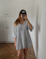 Vestido corto tejido a crochet con rayas horizontales blancas y negras, escote en V y mangas 3/4 acampanadas.