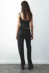 Pantalón de tiro alto color gris oscuro, con trabillas, bolsillos laterales y cierre frontal con cremallera, botón interior y ganchos metálicos.