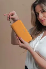 Billetera larga color beige de símil cuero, con cierre perimetral y bolsillo trasero con cierre.