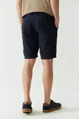 Bermuda de lino y algodón color beige, con bolsillos laterales y traseros, cierre con botón y presillas para cinturón.