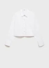 Camisa blanca de popelina de algodón, corte crop, con cuello camisero, manga larga con puños abotonados, bolsillo de parche en el pecho y cierre frontal con botones.