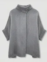 Capa o poncho tejido color verde esmeralda, con cuello polera alto que se cierra con un botón grande en el lateral. Presenta mangas cortas estilo japonesa y un calce amplio.