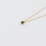 Conjunto de collar doble con cadena de oro amarillo 18k. El collar superior tiene un dije de zafiro engarzado en 4 puntas, y el collar inferior tiene un dije de flor negra con centro de zafiro.