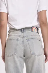 Pantalón de jean celeste de corte ancho, con detalles de ojalillos metálicos en la parte delantera.