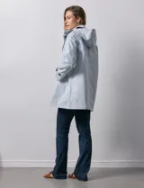 Gabardina color beige, impermeable, con abertura central con botones, bolsillos delanteros y capucha desmontable.