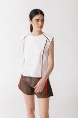 Blusa blanca sin mangas de lino 100% con cuello redondo y vivos marrones en los bordes.
