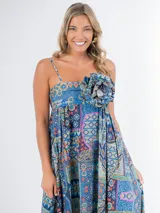 Vestido largo de algodón con estampado geométrico multicolor, corte cuadrado, elástico en la espalda y tirantes finos. Incluye aplique de flor desmontable.