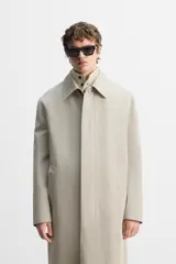 Gabardina color beige de corte relaxed fit, confeccionada en tejido italiano repelente al agua. Tiene cuello solapa, manga larga con puños abotonados, bolsillos de vivo en la cadera, bolsillo interior y abertura en la espalda.