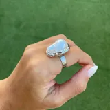 Anillo dorado con una perla irregular blanca.