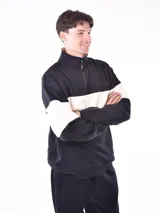 Buzo negro con cuello polo y cierre de cremallera parcial. Presenta una franja horizontal blanca en el pecho y mangas largas.