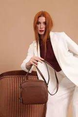 Bandolera de cuero sintético color beige, con diseño compacto y elegante. Cuenta con un bolsillo frontal con cierre y un compartimento principal con cierre. La correa es regulable.