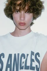 Camiseta gris jaspeado de corte amplio, cuello redondo y mangas cortas. Estampado frontal con la frase "Los Angeles 8500 Beverly Blvd, Los Angeles, CA 90048" en color azul.