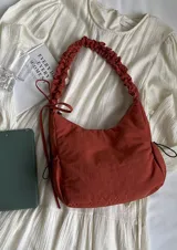 Cartera bandolera verde militar de nylon con textura sutil y manija fruncida.