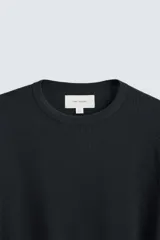 Camiseta blanca de manga larga con cuello redondo y textura cuadriculada.