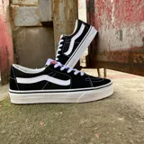 Zapatillas Vans SK8 Low negras con detalles en blanco, cordones blancos y suela de goma blanca.