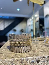 Pulsera tipo brazalete hecho en lentejuelas delgadas color borgoña y strass dorados.