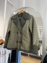 Chaqueta marrón con forro tipo corderito, doble botonadura y cuello con solapas.