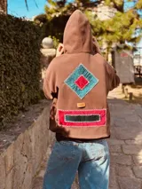 Canguro color chocolate de algodón con cierre parcial en el cuello y bolsillo frontal con apliques geométricos bordados a mano en terciopelo rojo y verde.