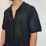 Camisa tejida de manga corta color verde oliva, con cuello tipo polo y cierre frontal con botones.