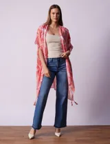Kimono tejido con estampado abstracto en tonos coral y blanco, con terminación de ruedo con borlas.